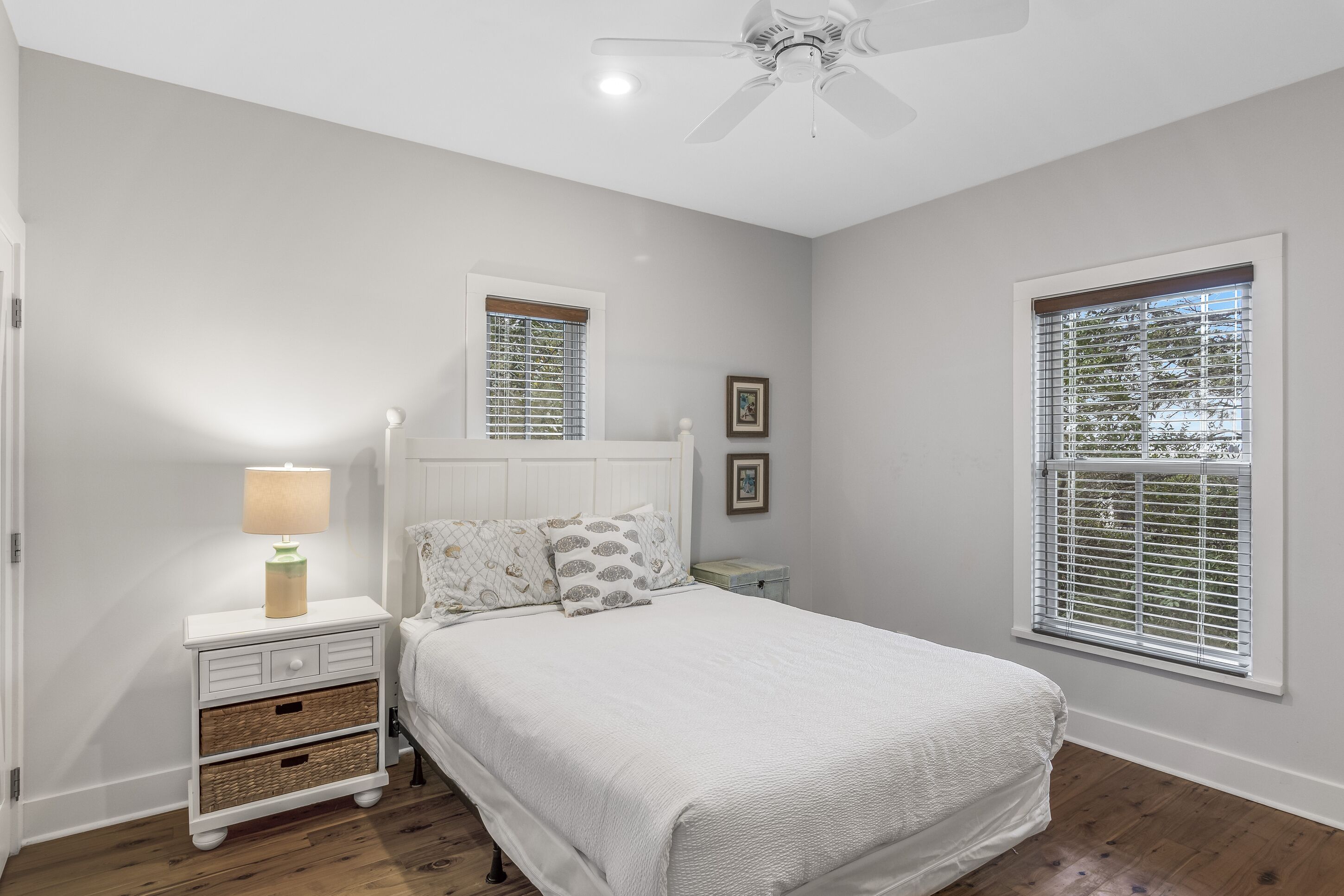 Un dormitorio con cama, mesitas de noche, lámpara y ventilador de techo.