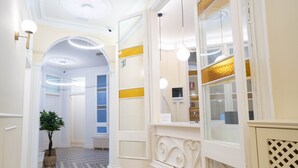 A hallway with a checkered floor, a potted plant, and a reception desk with a mirror and a sign. - Feelathome Casa Bertrand (Barcelona)