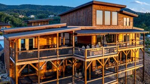 Una cabaña de madera de varios niveles con balcones, ventanas amplias y vistas del paisaje circundante.