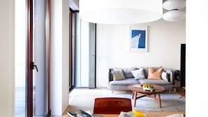 Ein modernes Wohnzimmer mit einer Couch, einem Couchtisch und einem großen Fenster.