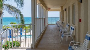 A covered corridor with white chairs and a pool on the left, leading to the beach. - Studio On The Beach - Heated Pool - Self Check-in (Belleair Beach)