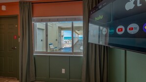 A hotel room with a view of the beach, a large screen displaying Hulu, and a door with a red sign. - Studio On The Beach - Heated Pool - Self Check-in (Belleair Beach)