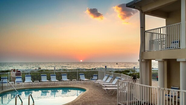A pool area with lounge chairs and a view of the sunset over the ocean. - Studio On The Beach - Heated Pool - Self Check-in (Belleair Beach)