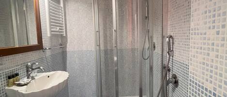 A bathroom with a glass-enclosed shower, a sink, and a toilet.