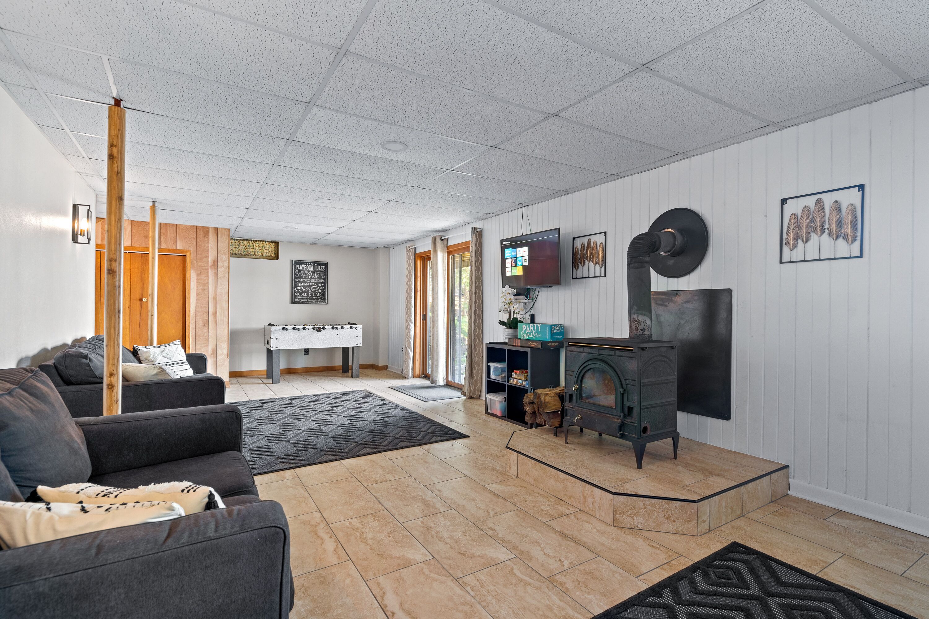 A living room with a sofa, a fireplace, a television, and a door leading to another room.