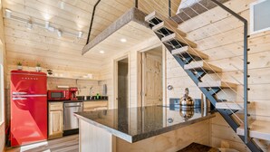 A modern kitchen with wooden walls, a red refrigerator, a stainless steel sink, and a glass-top island. - 2  Lake Cabins & Saunа & Access to Trails (Eagle River)