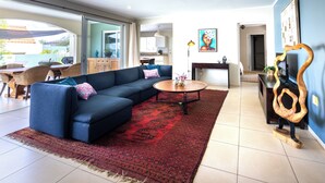 A modern living room with a blue sofa, a round coffee table, and a red patterned rug. - Salt Lake View - design villa with private pool in popular area (Jan Thiel)