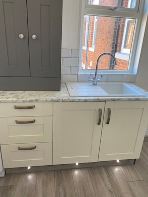 Modern kitchen with a sink, stainless steel faucet, and white and dark grey cabinetry.
