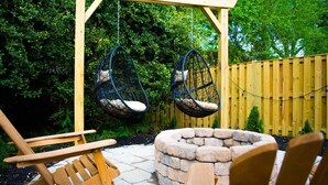A wooden pergola with two hanging chairs and a stone fire pit. - Entire Home Quiet Neighborhood
6 bedrooms, 8 beds, 3 bathrooms  (Alexandria)