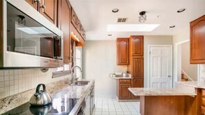 A modern kitchen with wooden cabinets, a built-in oven, and a stainless steel kettle on the countertop. - Entire Home Quiet Neighborhood
6 bedrooms, 8 beds, 3 bathrooms  (Alexandria)