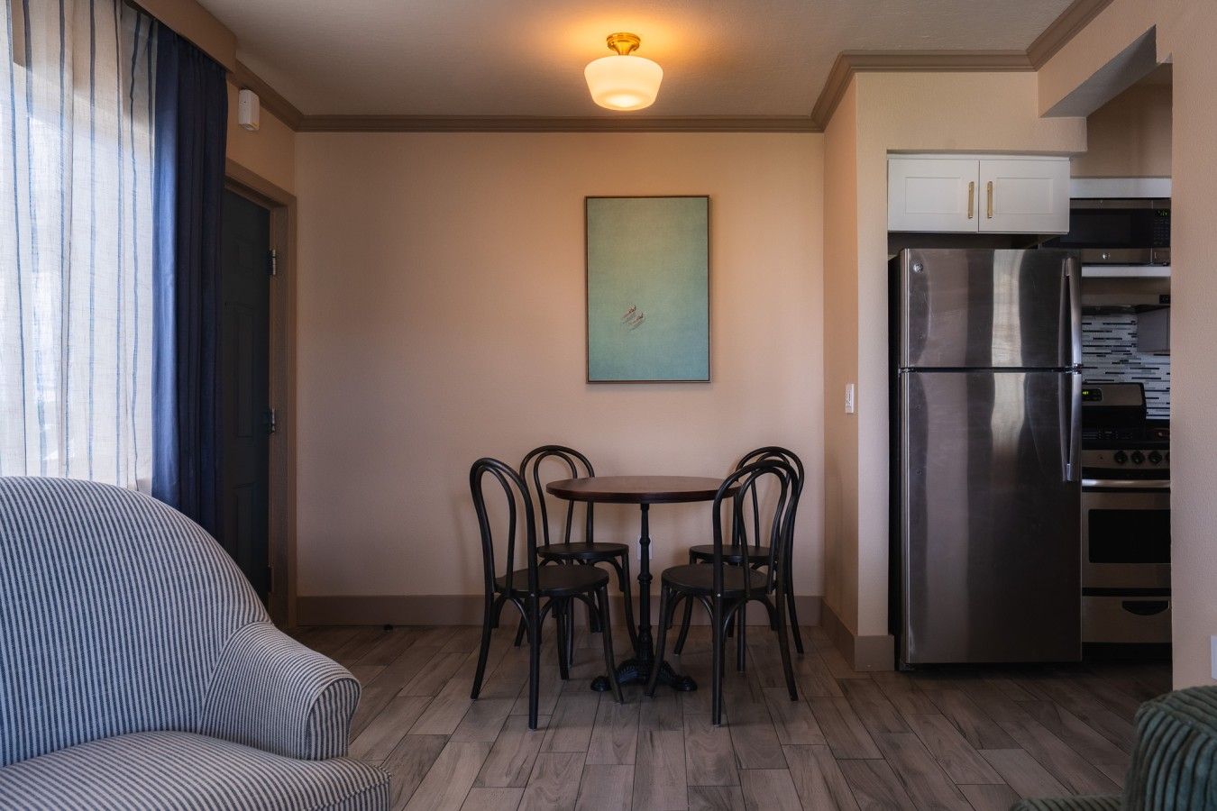 A compact living space with a dining table, four chairs, a sofa, a refrigerator, and a microwave.