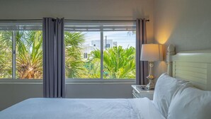 Una habitación de hotel con una cama, una mesita de noche con lámpara y una ventana con cortinas.