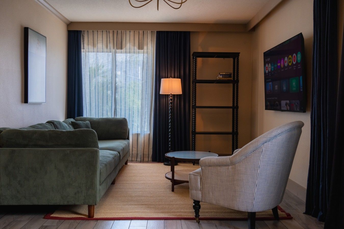 A living room with a sofa, armchair, lamp, and a bookshelf.