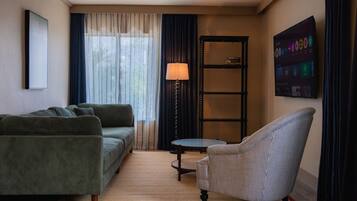 A living room with a sofa, armchair, lamp, and a bookshelf.