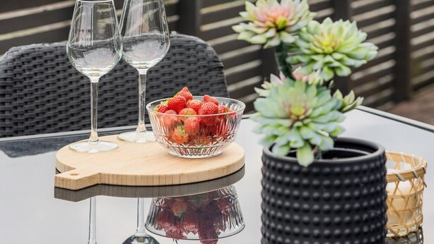 A table with two wine glasses, a bowl of strawberries, and a succulent plant. - Modern apartment with fantastic mountain and fjord  views! (Valestrandsfossen)