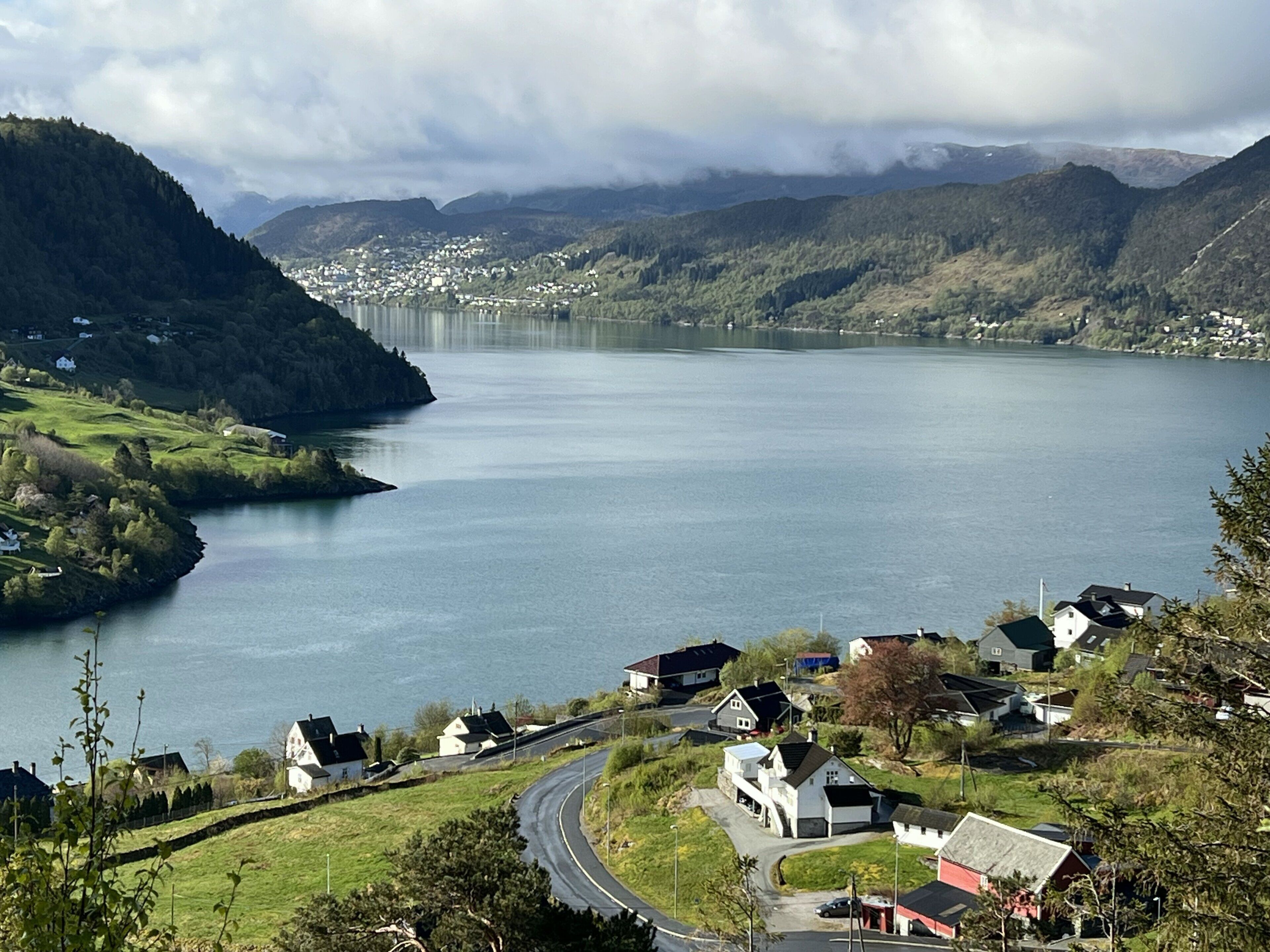 A coastal village with houses, a road, and a bridge in the distance.