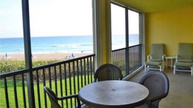A balcony with a view of the beach and ocean. There are two round tables and four chairs. - Turtle Reef Club Resort B (Jensen Beach)