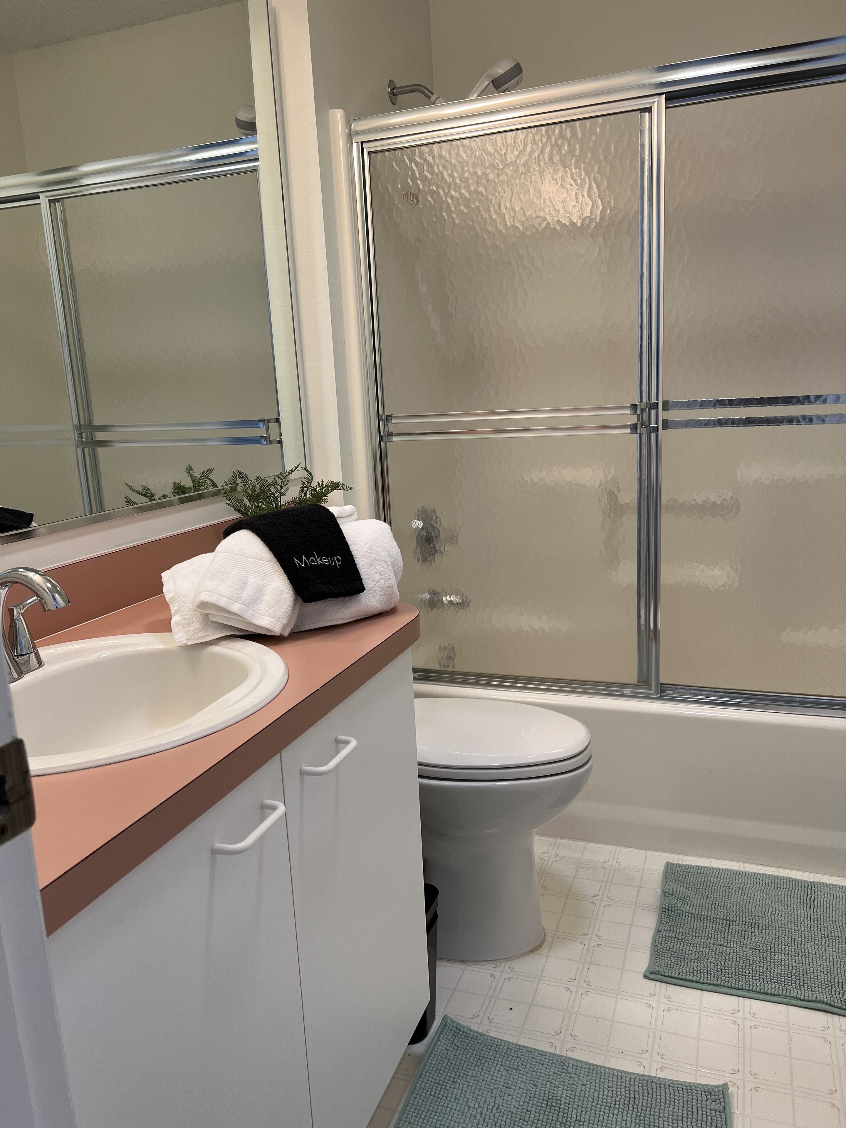 A bathroom with a sink, mirror, toilet, and shower.