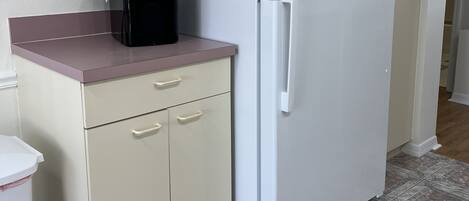 A kitchen with a white refrigerator, a microwave, and a sink.