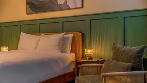 A neatly made bed with white linens, a green upholstered headboard, and two bedside lamps. - Studio On The Beach - Heated Pool - Self Check-in (Belleair Beach)