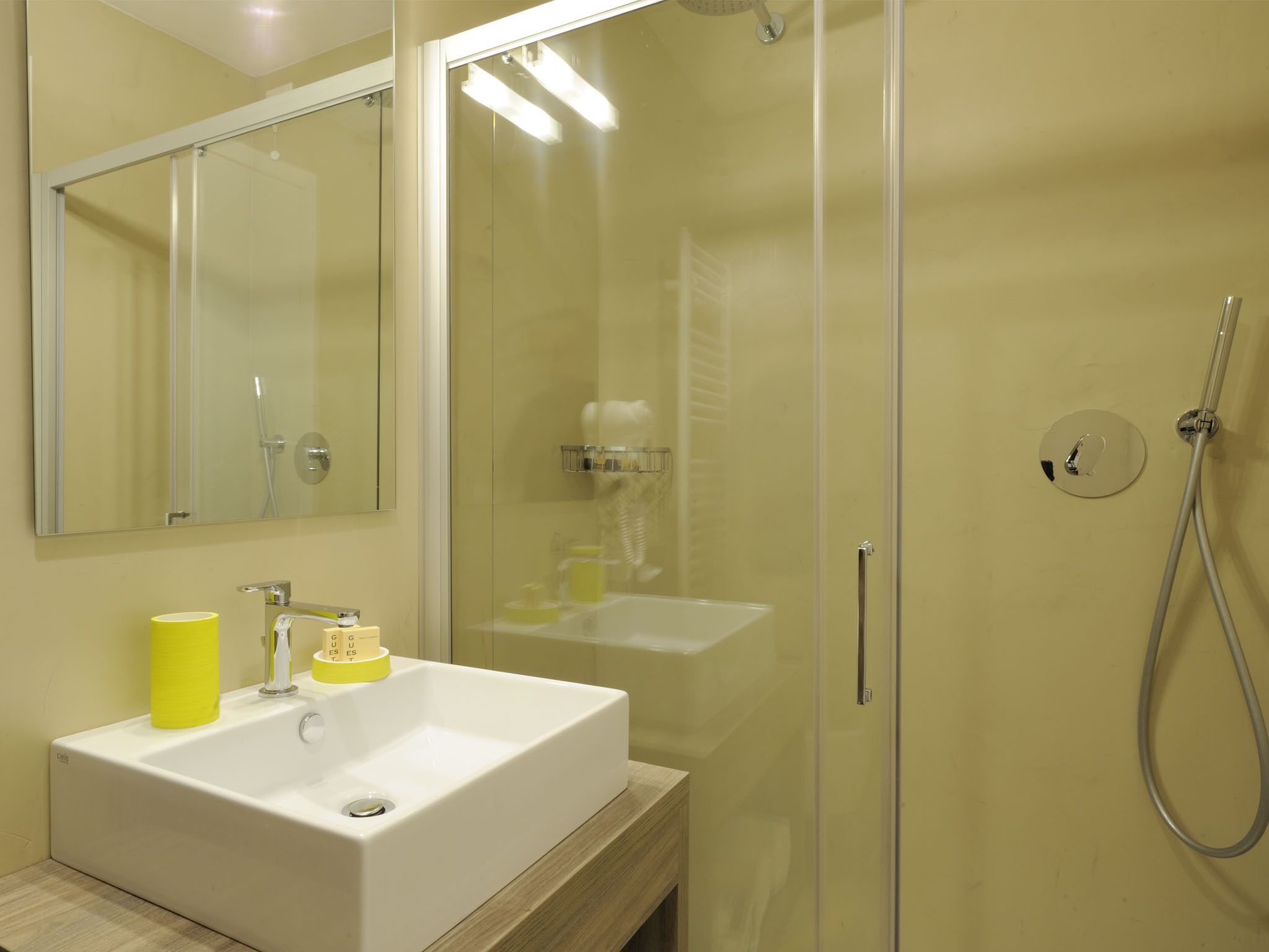 Ein modernes Badezimmer mit einer gläsernen Duschkabine, einem weißen Waschbecken und einem Spiegel darüber.