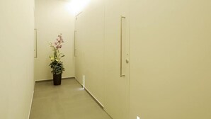 A hallway with a potted plant, a door with the number 212, and a light fixture on the ceiling. - Hotel Concordia (Loano)