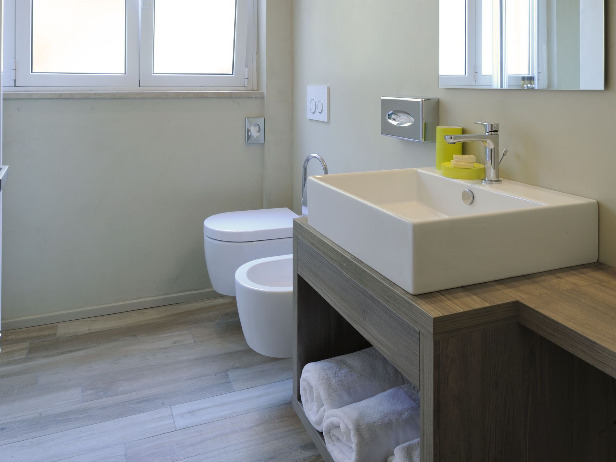 A modern bathroom with a white sink, a toilet, and a mirror above the sink.