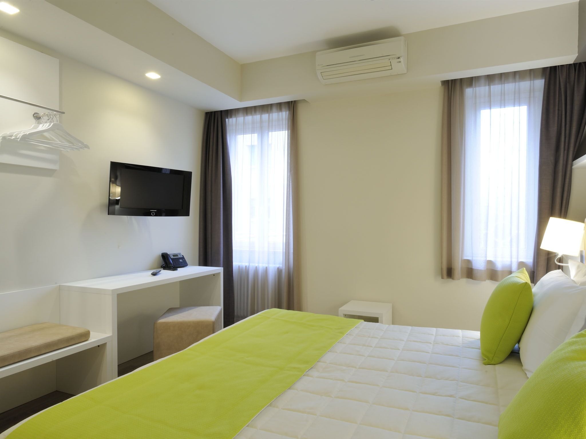 Une chambre d’hôtel équipée d’un lit, d’un bureau, d’une télévision et d’un appareil de climatisation.