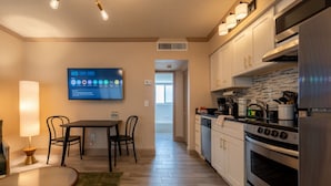 A modern kitchen with stainless steel appliances, a dining area with a table and chairs, and a television mounted on the wall. - Condo On The Beach - Heated Pool - Self Check-in (Belleair Beach)