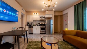 A compact living space with a kitchenette, a dining area, a sofa, and a TV displaying entertainment apps. - Condo On The Beach - Heated Pool - Self Check-in (Belleair Beach)