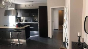 Una cuina moderna amb armaris foscos, una illa central amb tamborets i il·luminació penjant.