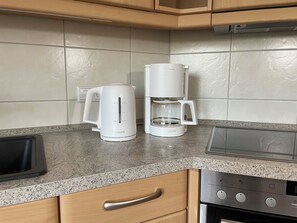A kitchen with a coffee maker, kettle, and a microwave.