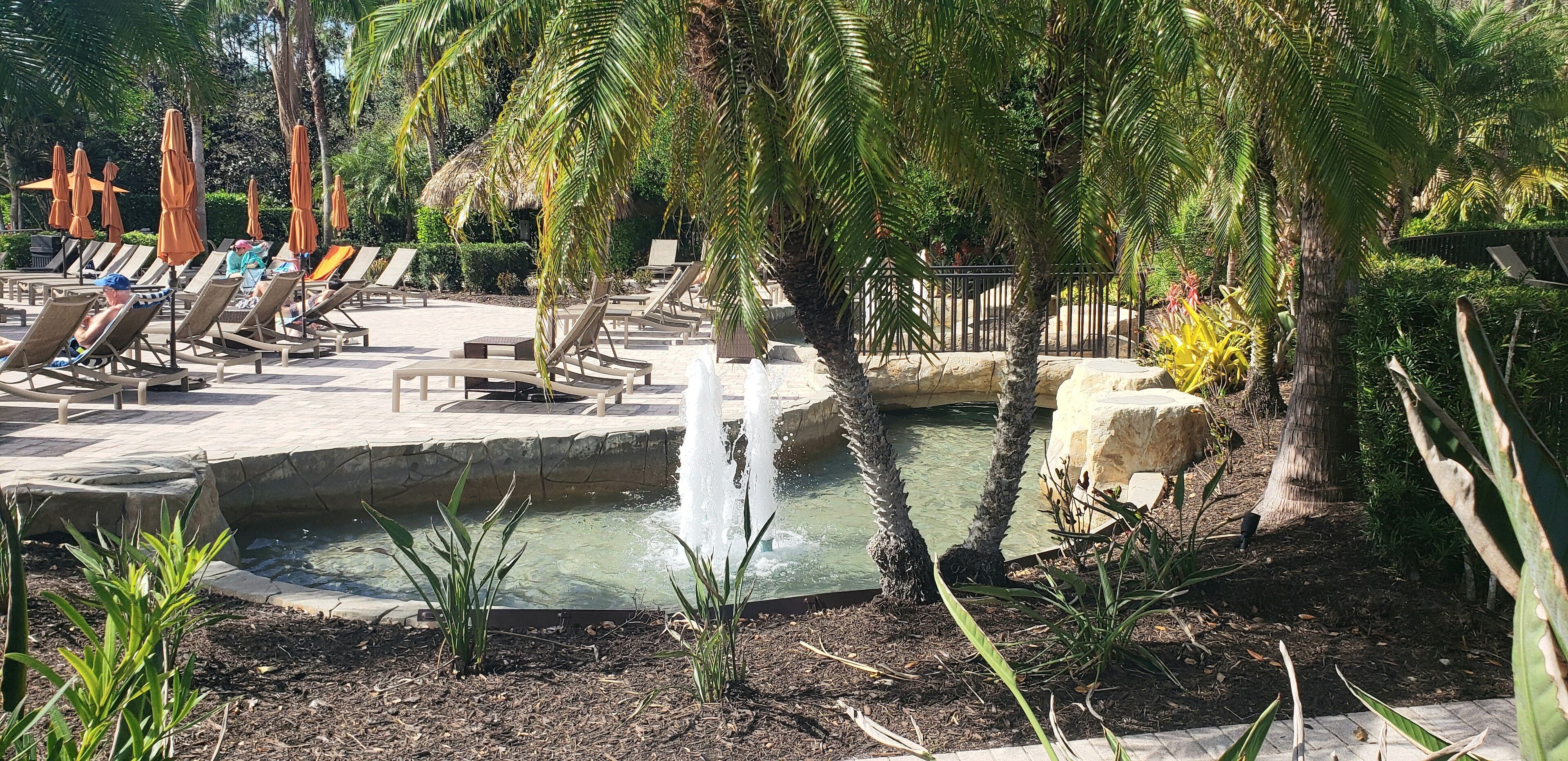 A pool area with lounge chairs and a water feature.