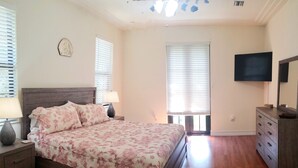 Un dormitorio con cama, mesitas de noche, cómoda, televisor y ventilador de techo.