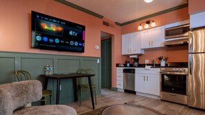 A compact kitchen with a refrigerator, oven, microwave, and a dining area with chairs and a table. - Condo On The Beach - Heated Pool - Self Check-in (Belleair Beach)