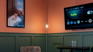 A cozy room with a sofa, two round tables, a chair, a TV displaying Hulu, and a wall-mounted lamp. - Condo On The Beach - Heated Pool - Self Check-in (Belleair Beach)
