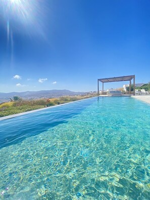 Une piscine d’un bleu éclatant, agrémentée d’une pergola et de chaises longues, le tout entouré d’un paysage pittoresque.