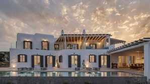 A modern two-story house with a swimming pool, large windows, and a covered outdoor seating area. - Aura villa A story to tell  (Mykonos)