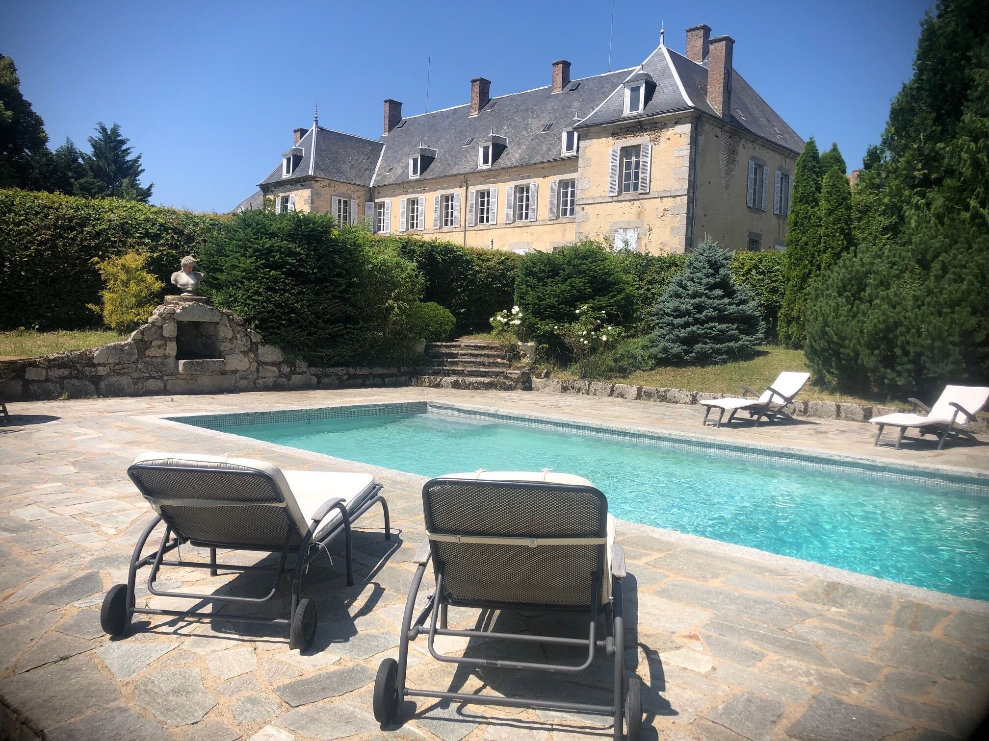 A pool area with lounge chairs and a stone building in the background.