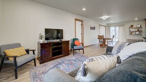 Un salón espacioso con sofá, sillón y televisor sobre un mueble de madera.