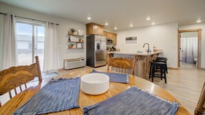 Una cocina moderna con armarios de madera, un refrigerador y un microondas. Hay un comedor con una mesa redonda y manteles individuales azules.