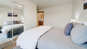 Un dormitorio con cama, espejo y vista a la cocina.