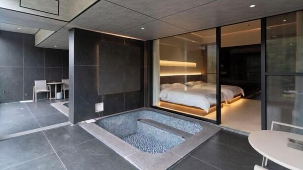 A modern hotel room with a large bathtub, a bed, and a glass partition. - Retang Village Longfa Hot Spring Villa (Huidong)