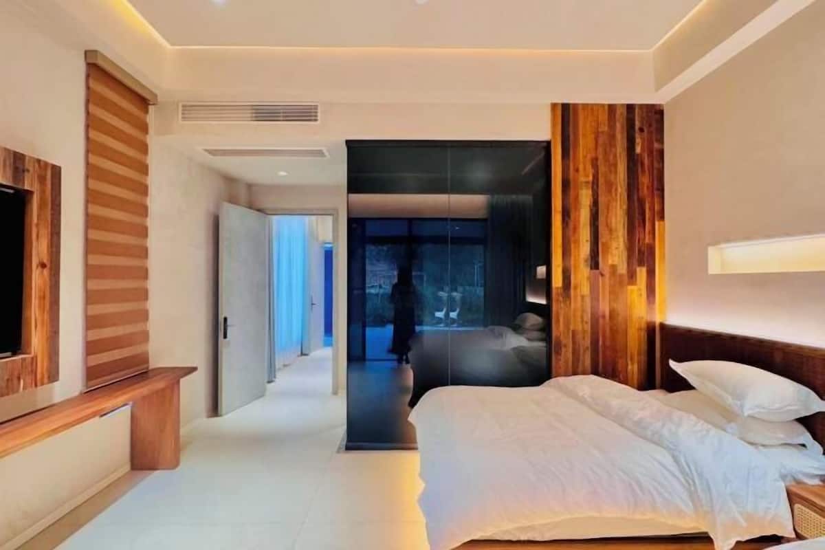 A modern hotel room with a bed, a TV, and a wooden accent wall.