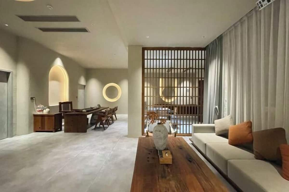 A modern living room with a wooden coffee table, a sofa, and a dining area with chairs and a table.