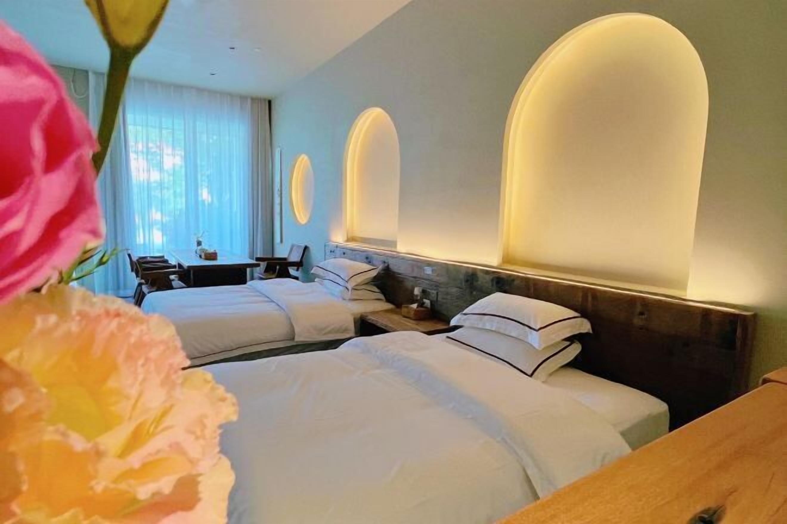 Een hotelkamer met twee bedden, een houten nachtkastje, een bureau en een stoel.