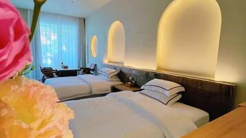 A hotel room with two beds, a wooden nightstand, a desk, and a chair.