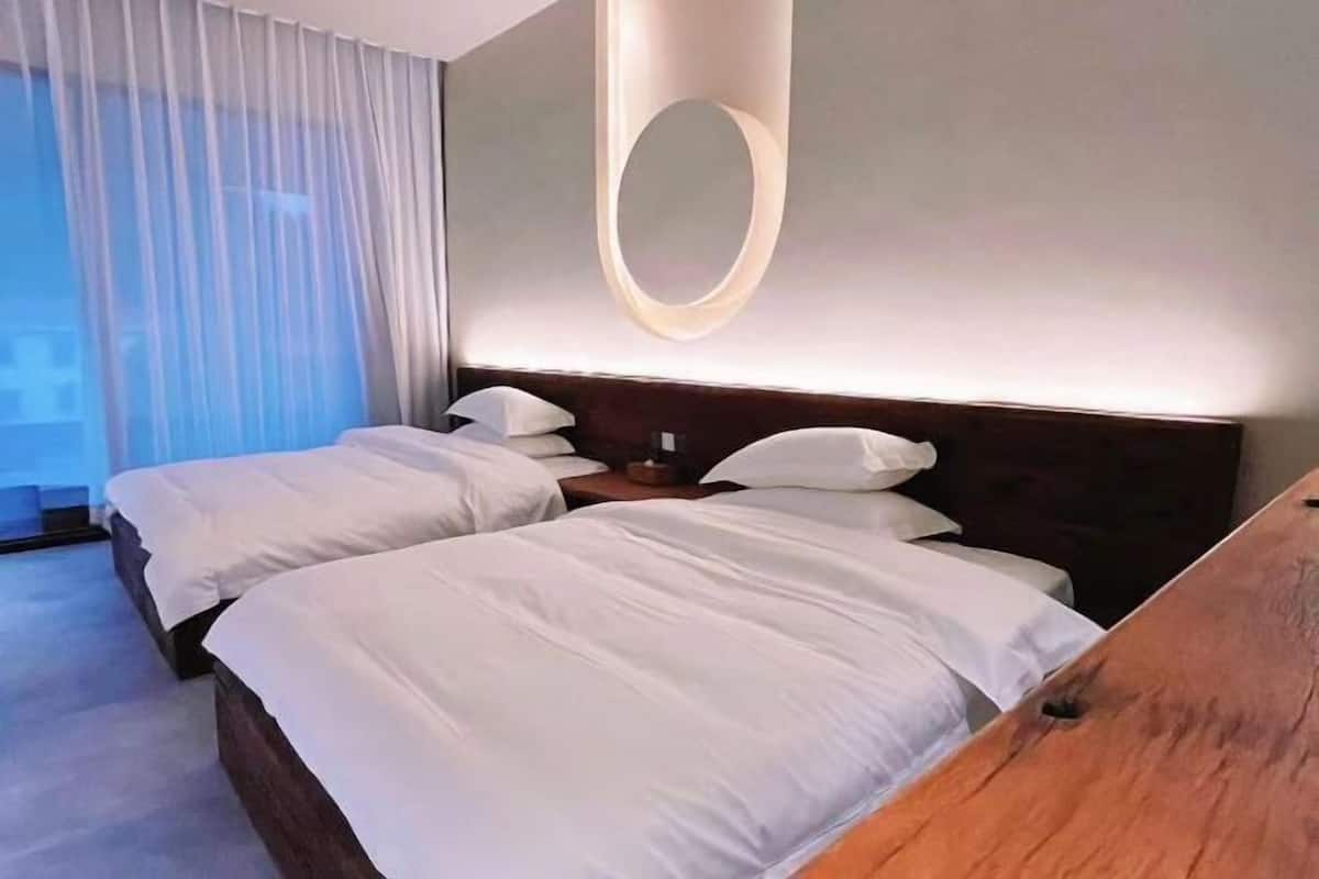 A hotel room with two beds, a large mirror, and a view of the outdoors.