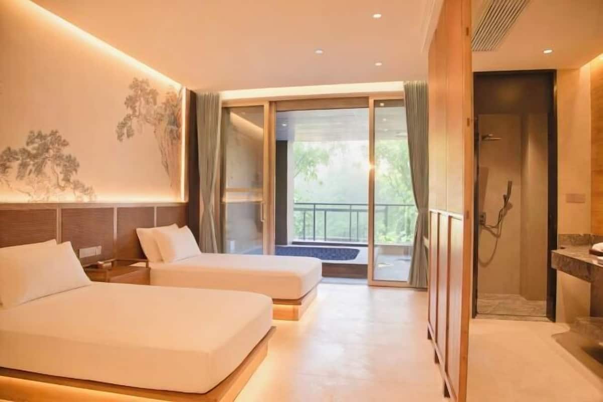 A hotel room with two beds, a shower, and a balcony with a view.