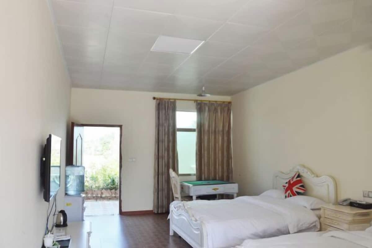 A hotel room with a bed, bedside table, and a desk with a chair.
